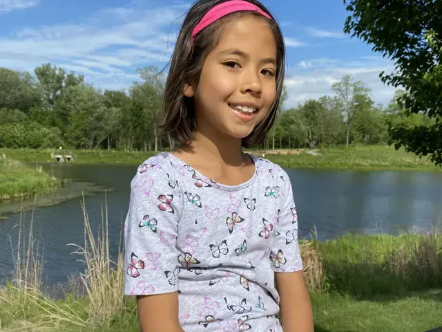 Family photo: child seated beside a pond