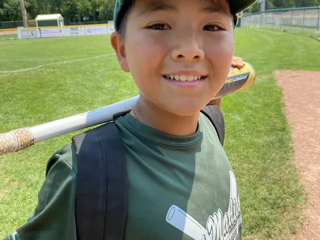 Family photo: young baseball player smiling at the ballpark