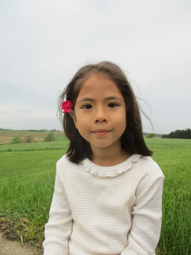 Family photo: child standing in a green field